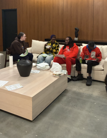 Group of four people sitting on a couch, engaged in conversation in a modern setting.